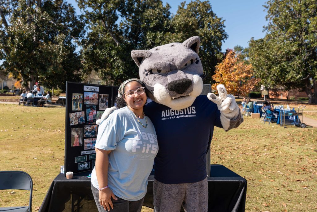 Augusta University mascot, Augustus, with a student outside on campus. 
