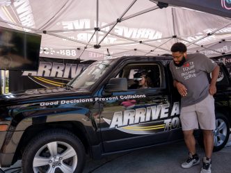 A woman wearing virtual reality goggles sits in a stationary vehicle.