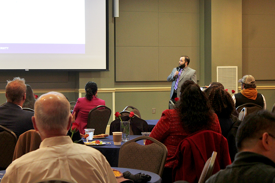 A college-aged man presents to a large room of people.