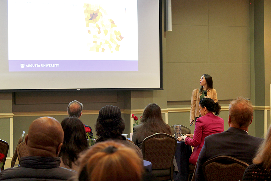 A college-aged woman presents to a large room of people.