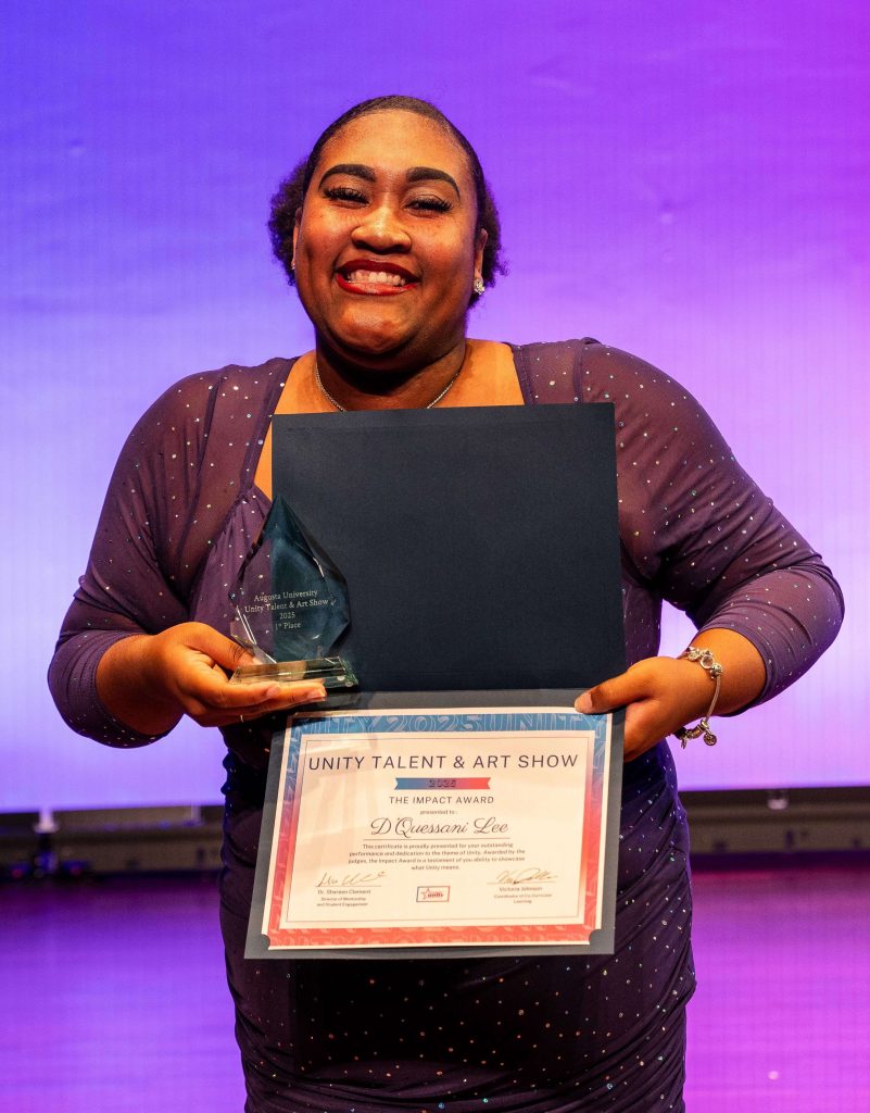 A smiling woman holds a certificate and trophy.