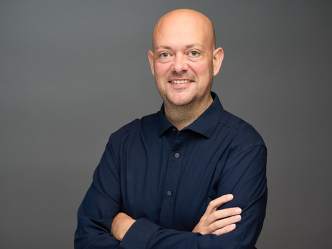 A man stands with his arms crossed in front of him.