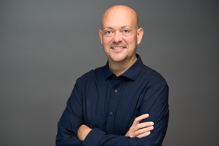 A man stands with his arms crossed in front of him.