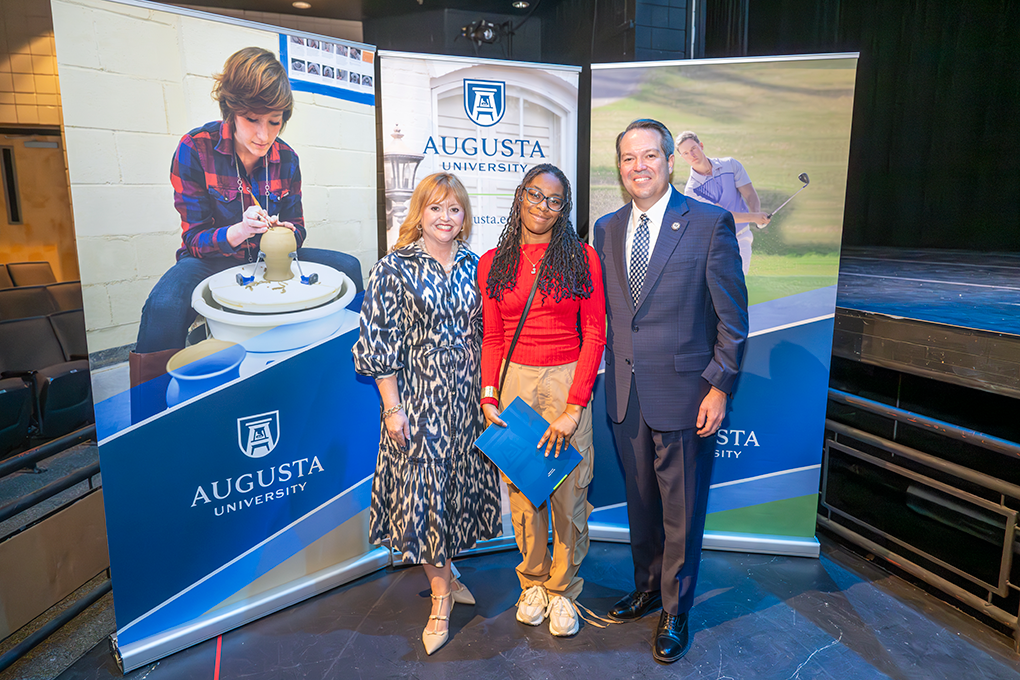 A university president and first lady pose with a high school student.