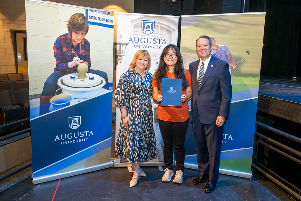 A university president and first lady pose with a high school student.