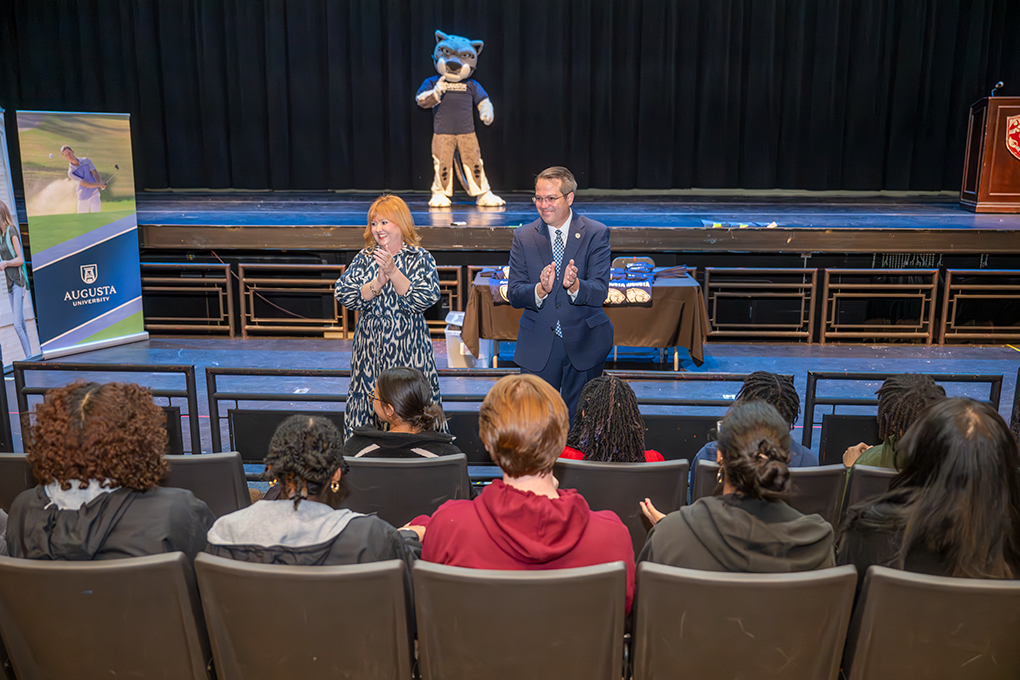 A university president and first lady speak to a group of high school students.