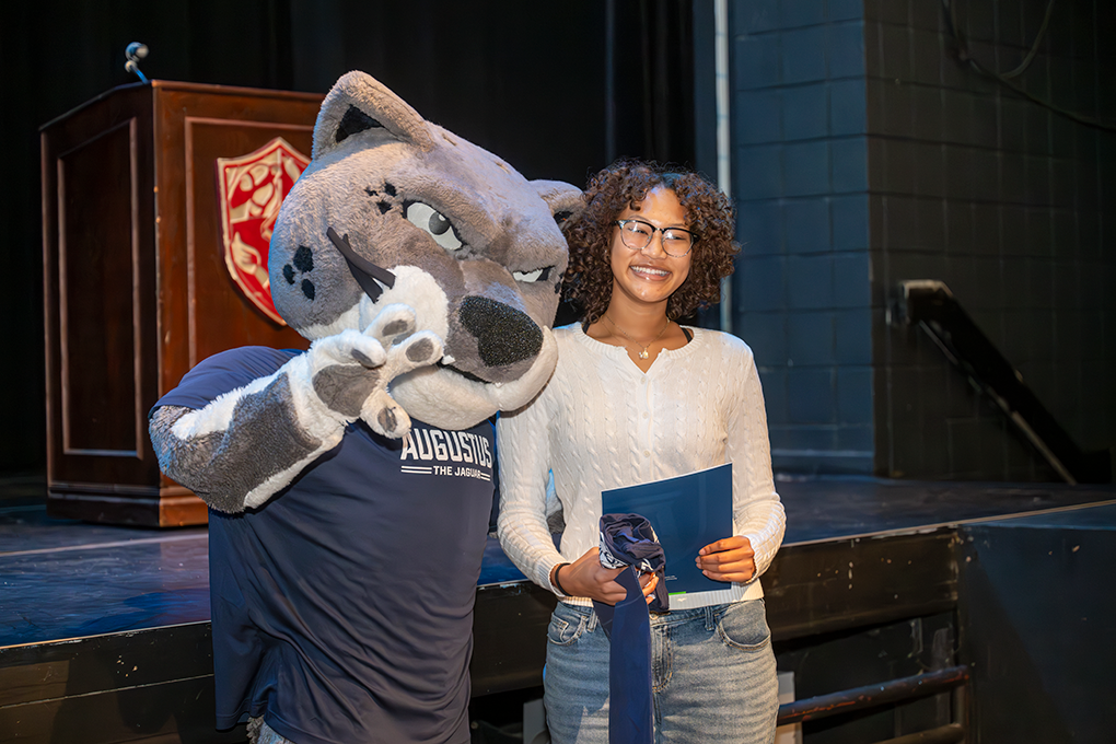 A high school girl poses with a Jaguar university mascot.