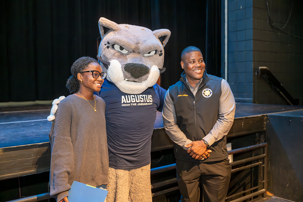 A high school girl and her father pose with a Jaguar university mascot.