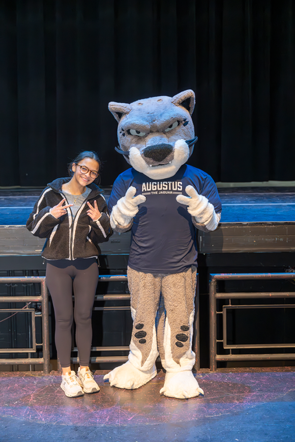 A high school girl poses with a Jaguar university mascot.