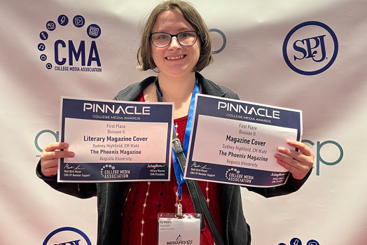 A college-aged woman holding up two paper certificates