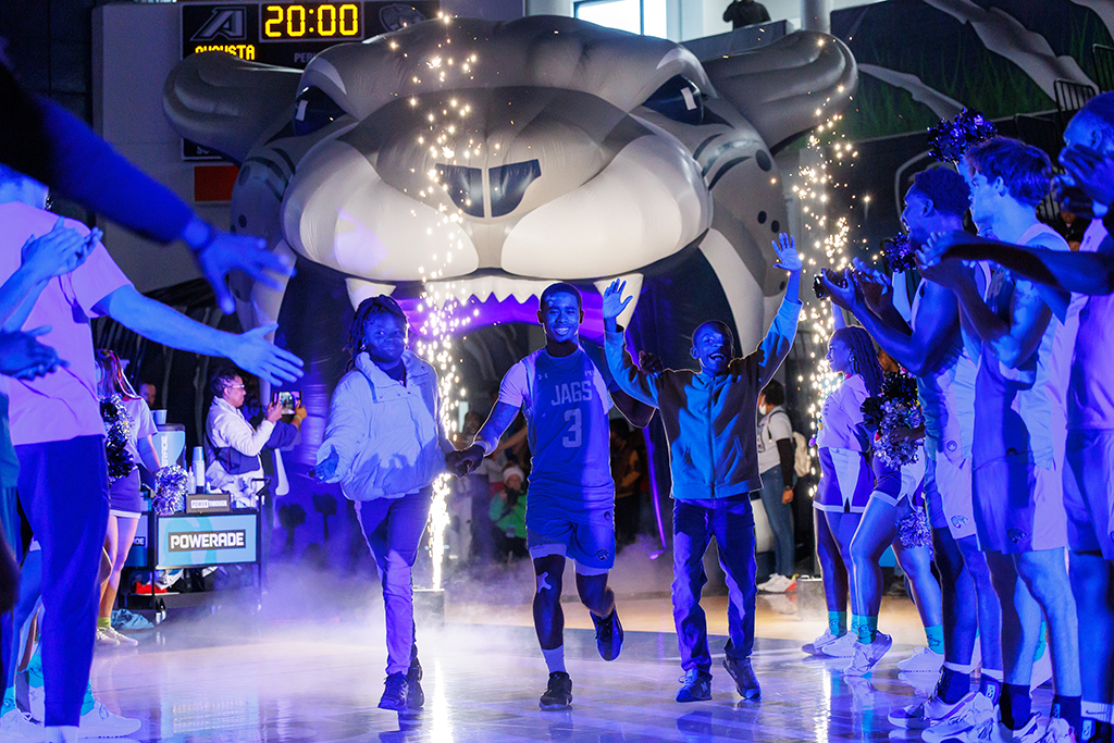 A basketball player running onto the court with a two fifth-graders