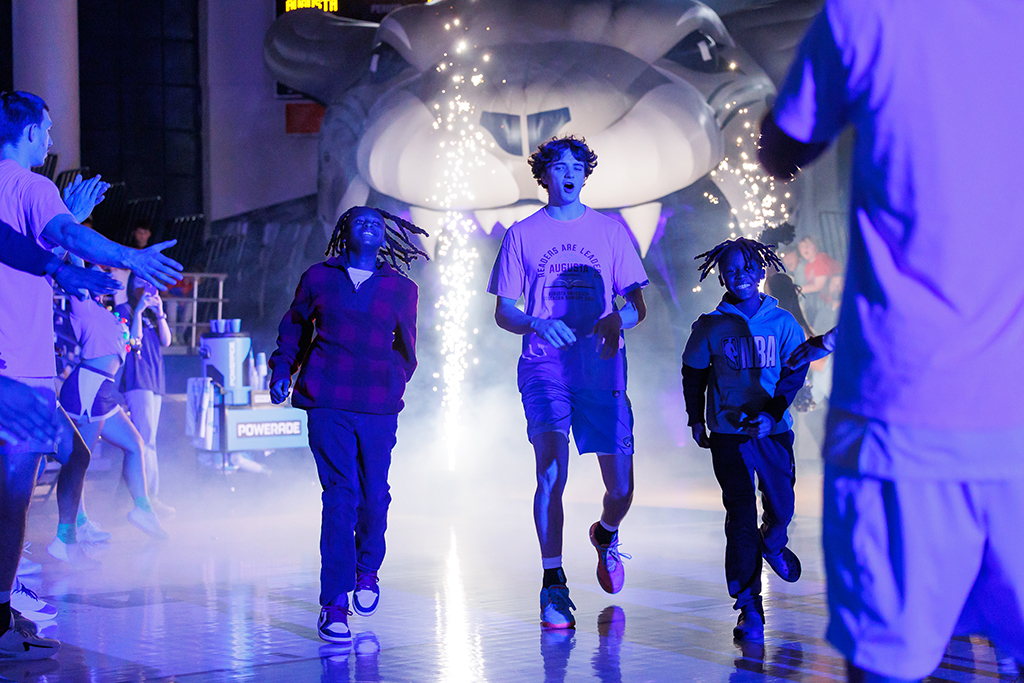 A basketball player with two fifth-grade students during introductions