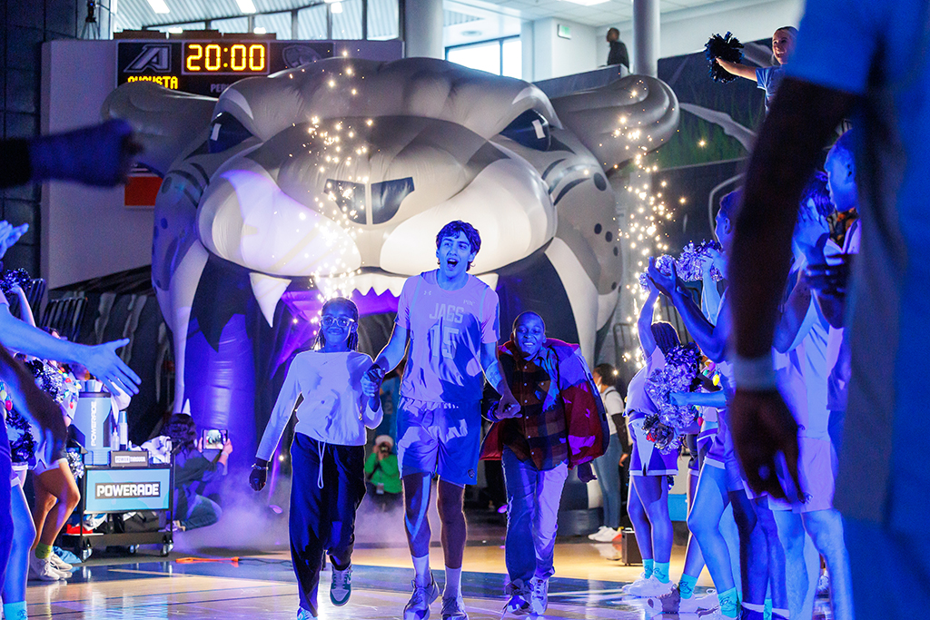 A basketball player running onto the court with a two fifth-graders