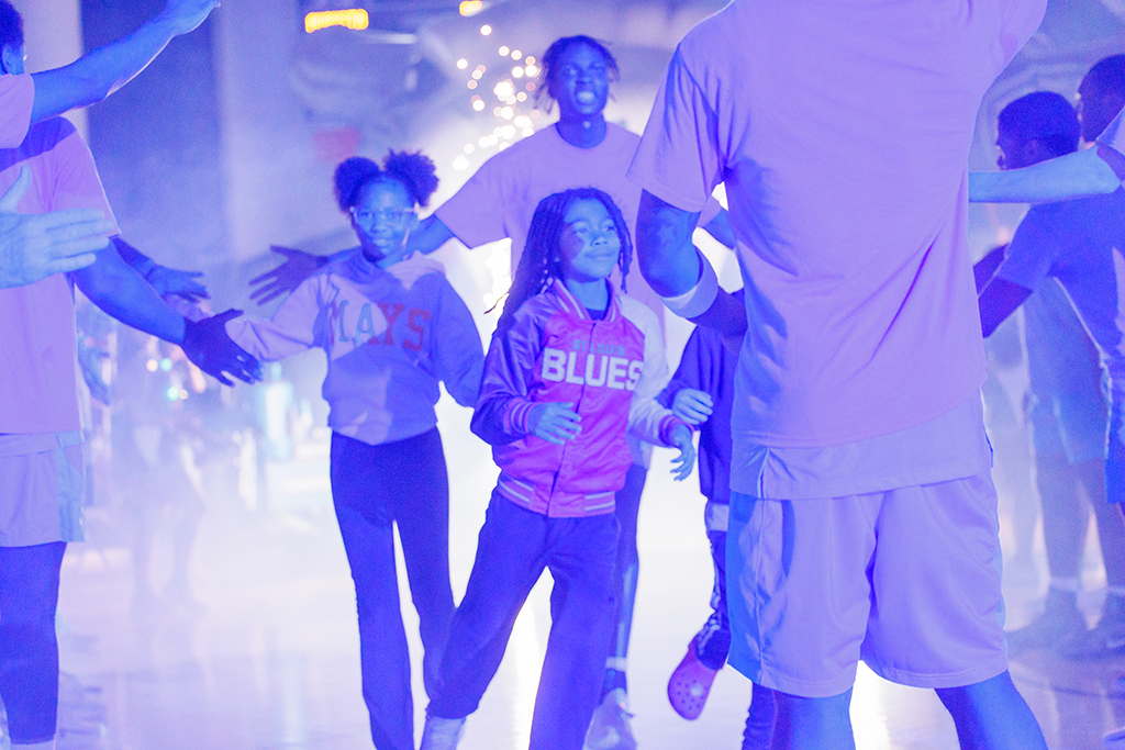 A basketball player with two fifth-grade students during introductions
