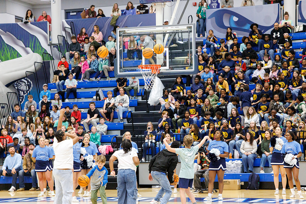 Boys and girls shooting basketballs at a goal