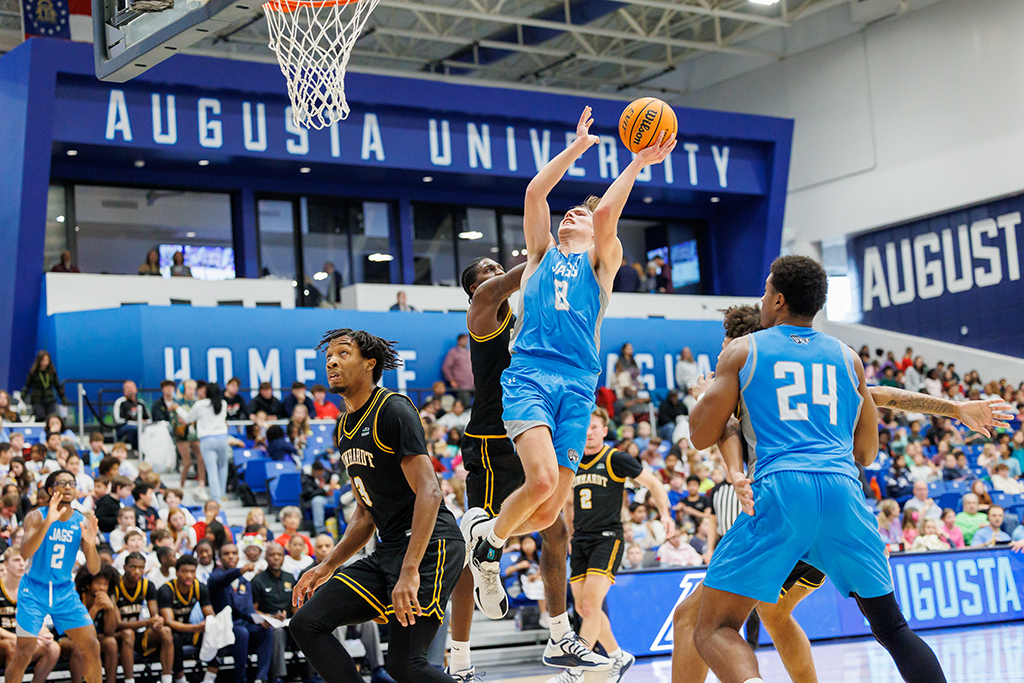 A Jaguar basketball player shoots over their opponent