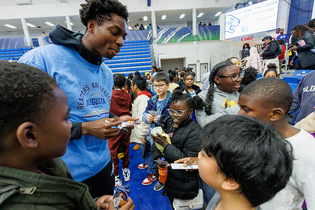 A basketball player signing autographs for boys and girls