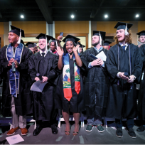 group of male and female students standing in graduation caps and gowns.