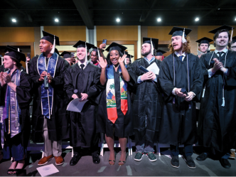 group of male and female students standing in graduation caps and gowns.