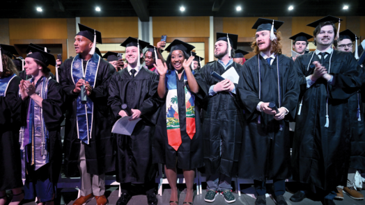 group of male and female students standing in graduation caps and gowns.