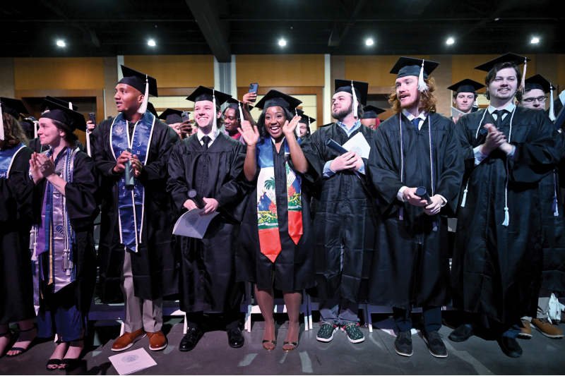 group of male and female students standing in graduation caps and gowns.