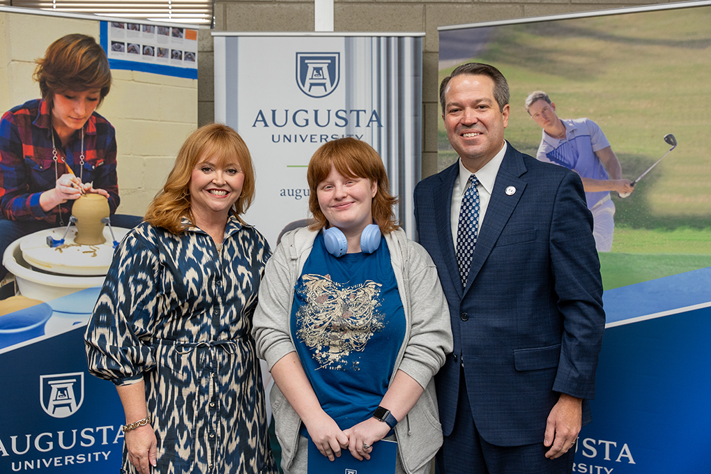 A university president and first lady pose with a high school student.
