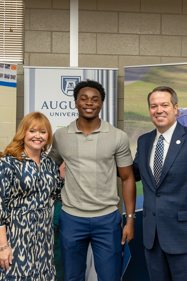 A university president and first lady pose with a high school student.