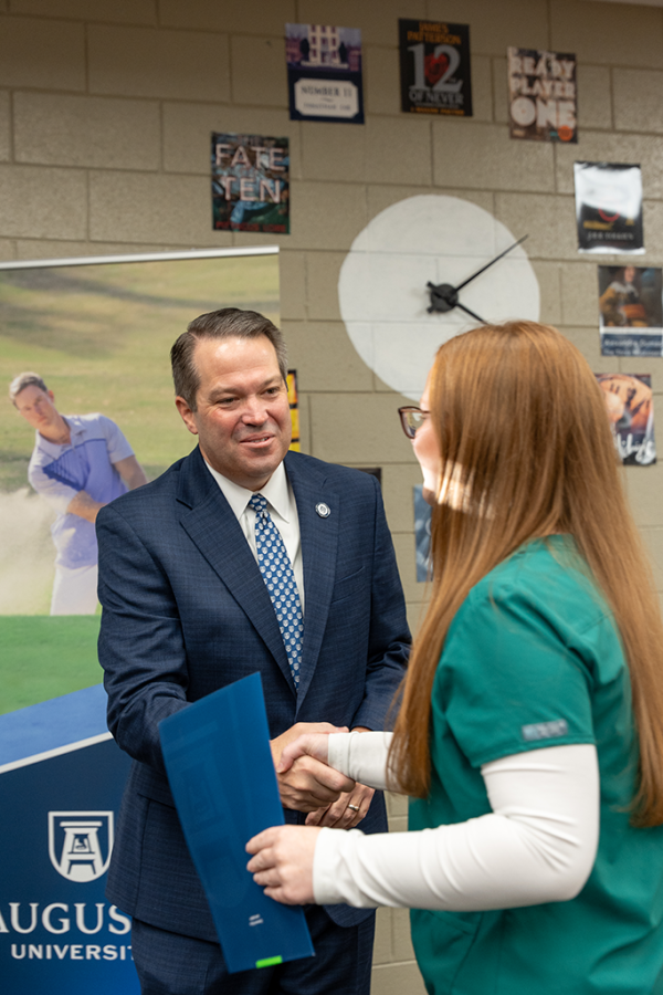 A university president and first lady pose with a high school student.