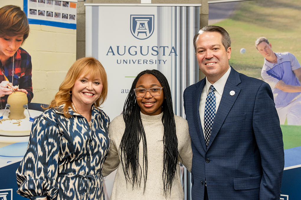 A university president and first lady pose with a high school student.