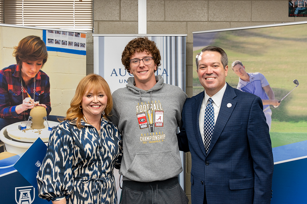 A university president and first lady pose with a high school student.