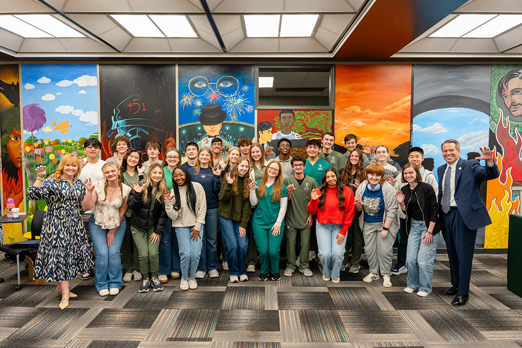 A group of high school students and a university president and first lady pose for a photo.