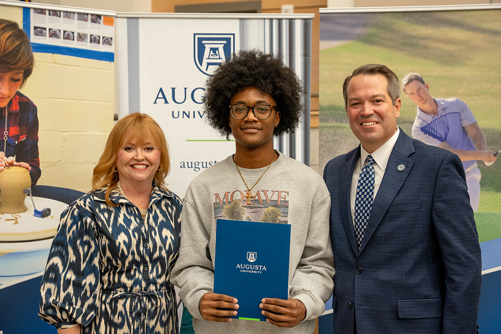 A university president and first lady pose with a high school student.