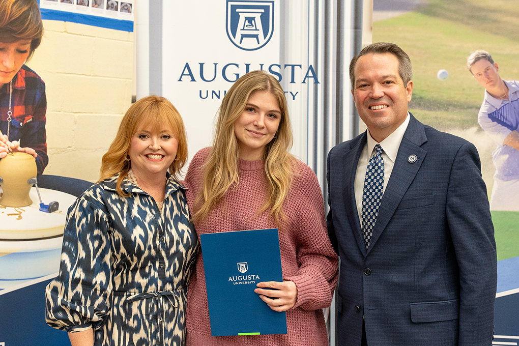 A university president and first lady pose with a high school student.