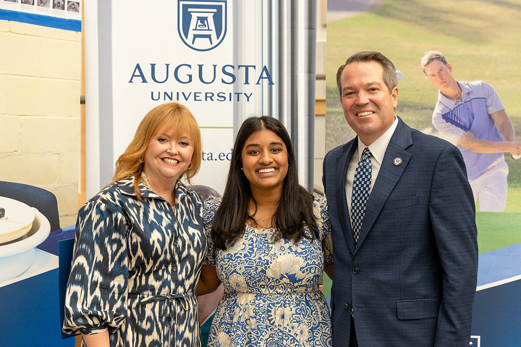A university president and first lady pose with a high school student.