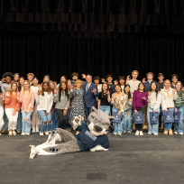 A group of high school students and a university president and first lady pose for a photo.