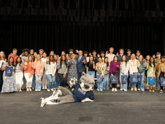 A group of high school students and a university president and first lady pose for a photo.