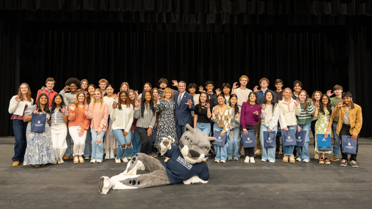 A group of high school students and a university president and first lady pose for a photo.