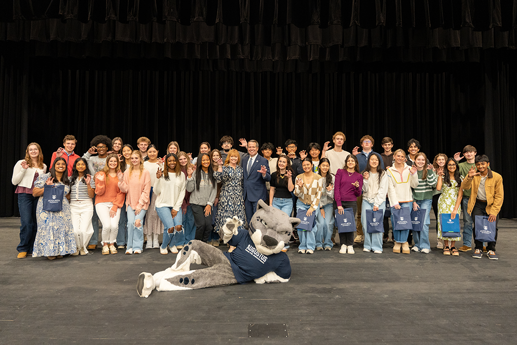 A group of high school students and a university president and first lady pose for a photo.