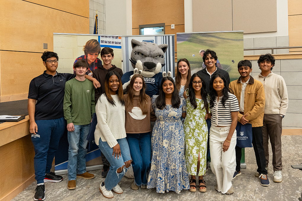 A group of high school students pose with a Jaguar university mascot.