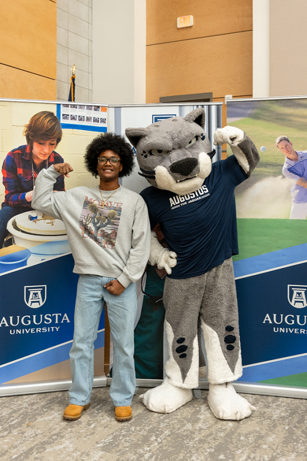 A high school boy poses with a Jaguar university mascot.