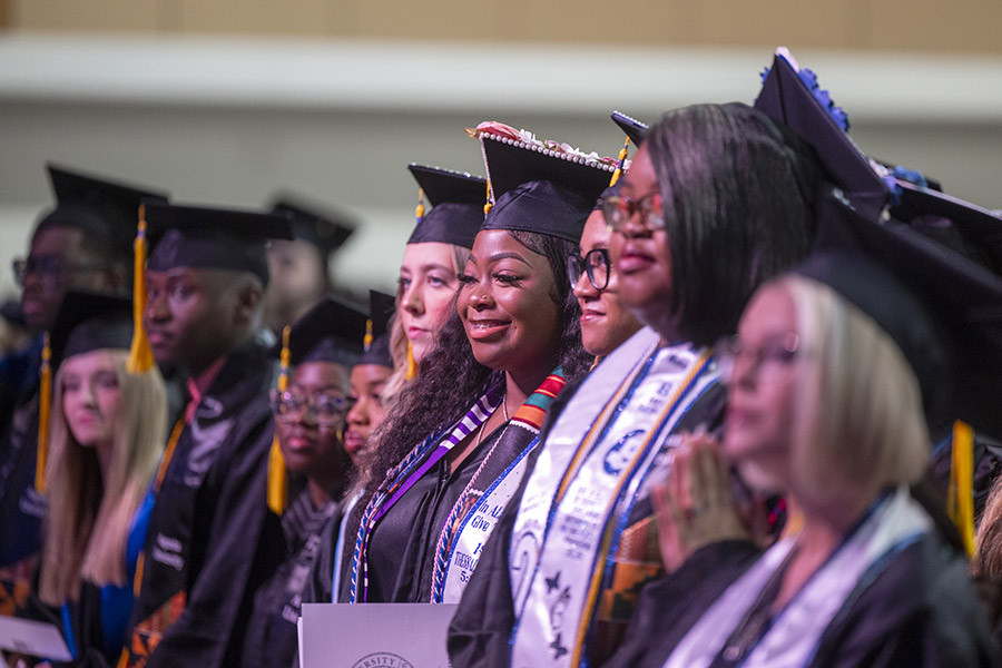 students in graduation caps and gowns standing. 
