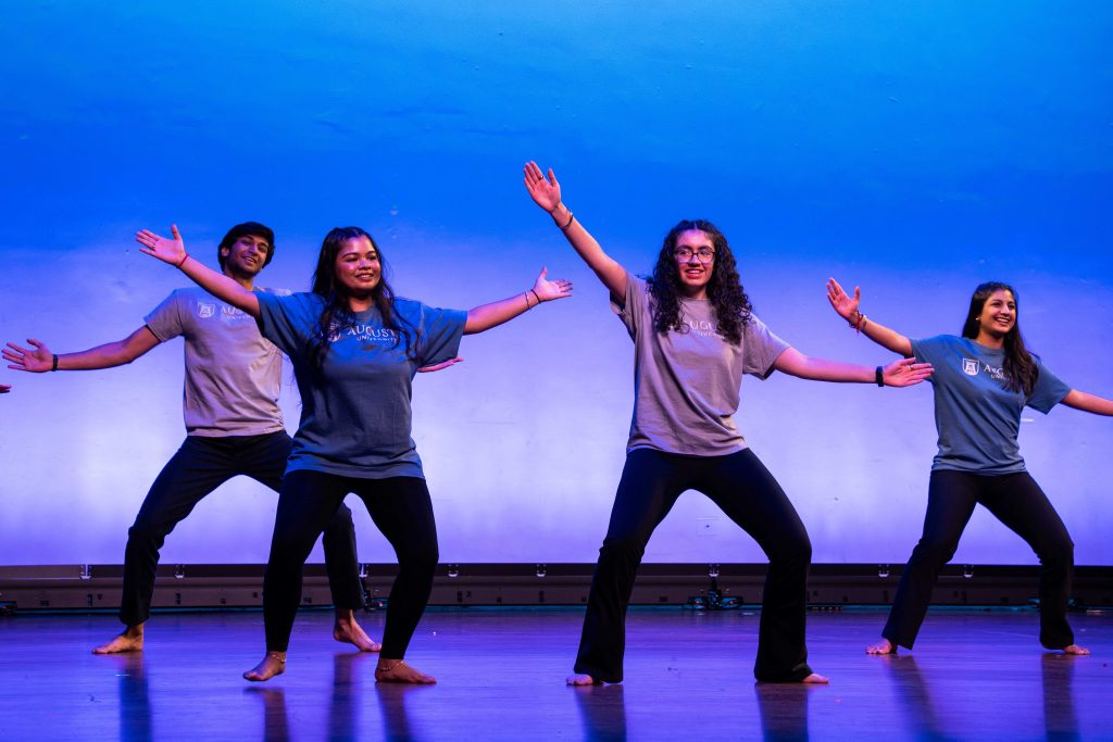 A group of men and women on stage dancing
