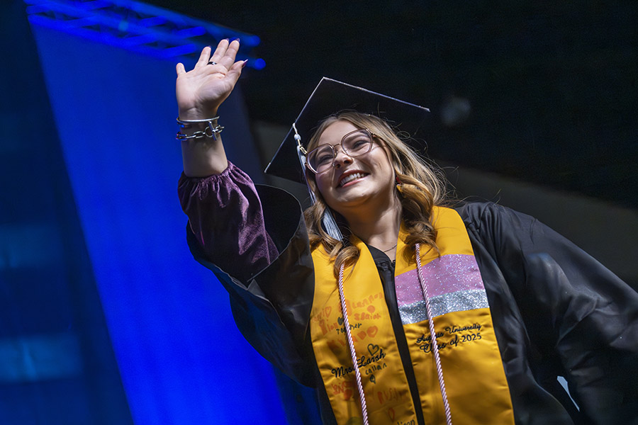 Female in a graduation cap and gown waving. 