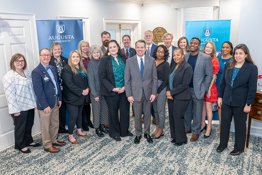 A large group of university leaders gather inside a spacious conference room.