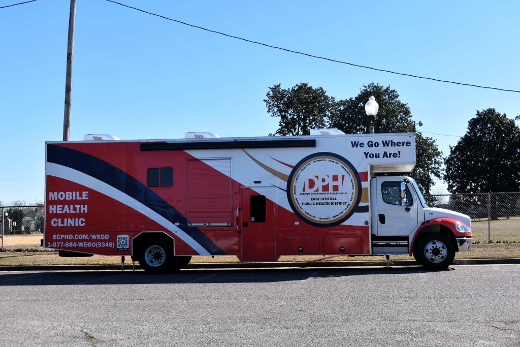 A large red and white truck with the words Mobile Health Clinic and DPH on the side