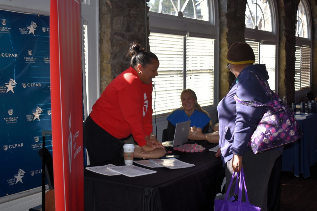 A woman demonstrates CPR on a CPR dummy