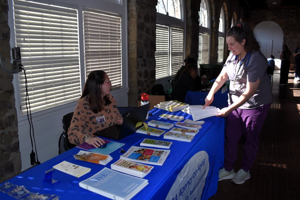 Two women speak to each other across a vendor table