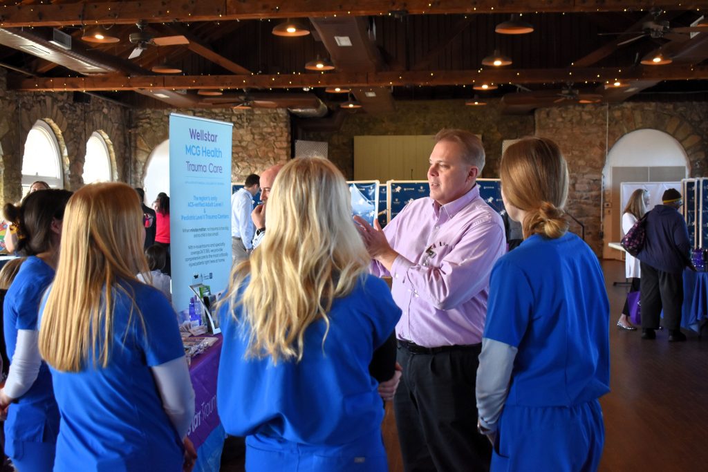 A man speaks to a group of girls wearing scrubs