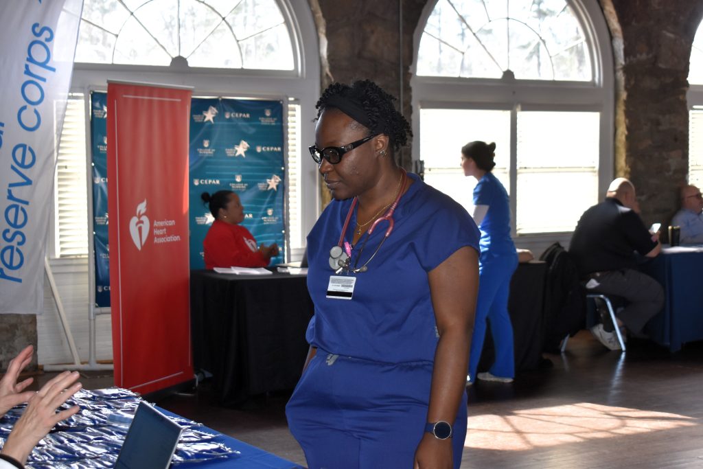 Woman in scrubs and a stethoscope in front of a table