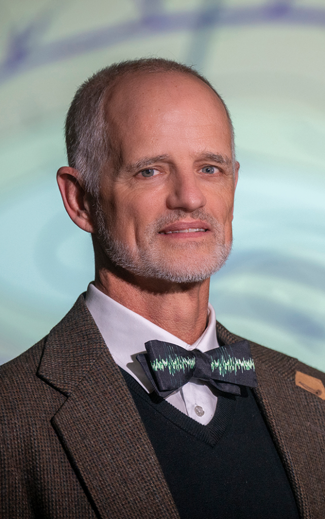 A male neuroscientist wearing a bowtie smiles at the camera.